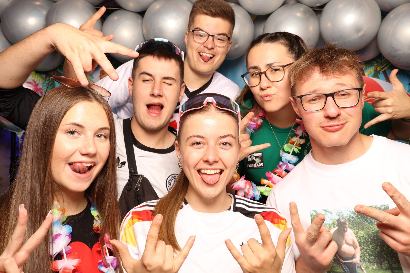 Fotobox: Gruppe mit Blumenketten vor einem Strand-Motiv mit Ballons