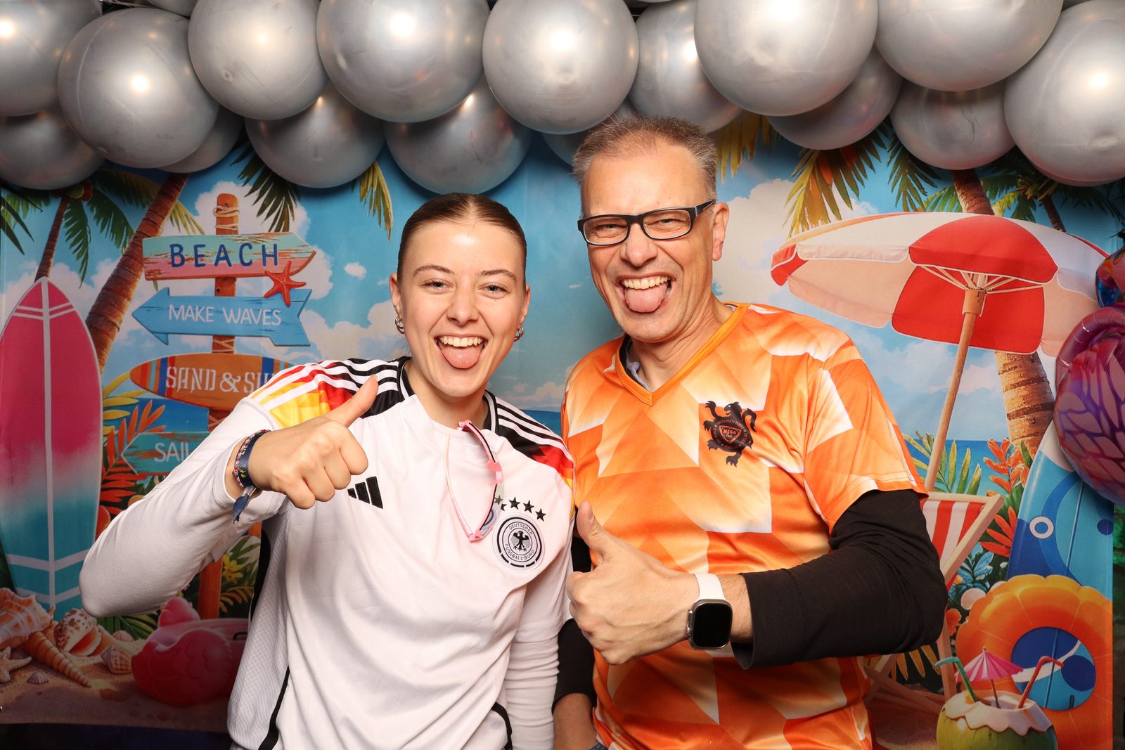 Fotobox: Zwei Gäste in Fußballtrikots vor einem Strand-Motiv