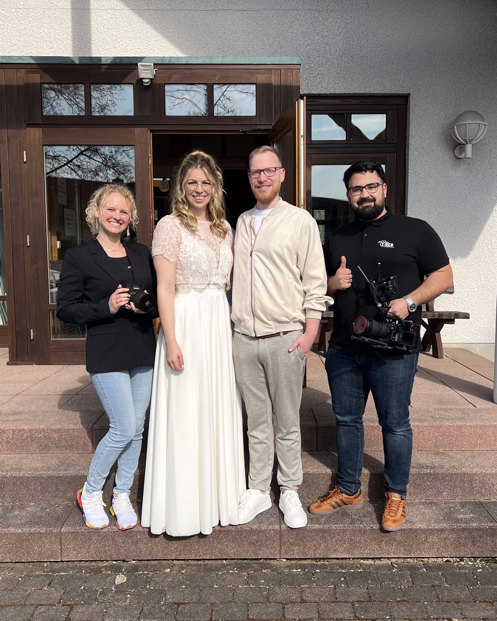 Vanessa mit Fotokamera und Devran mit Filmkamera neben einem Brautpaar